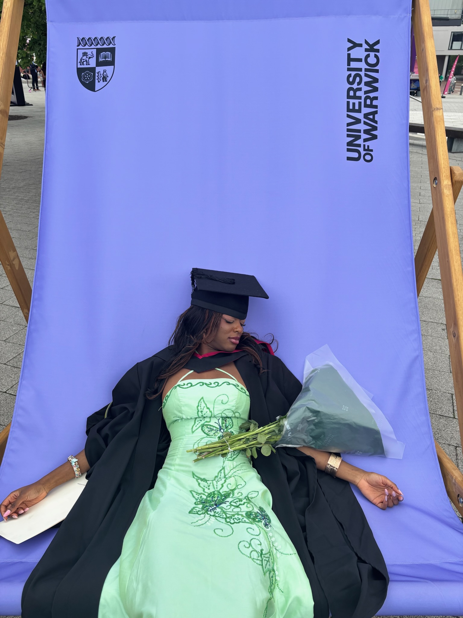 Recent graduate sitting slumped on a chair holding flowers and a degree, looking exhausted but accomplished — introducing my blog about post-graduation life, self-growth, and new beginnings