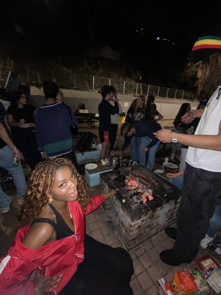 Student grilling meat at a Hong Kong seaside barbecue with friends relaxing, eating, and drinking—study abroad experience.
