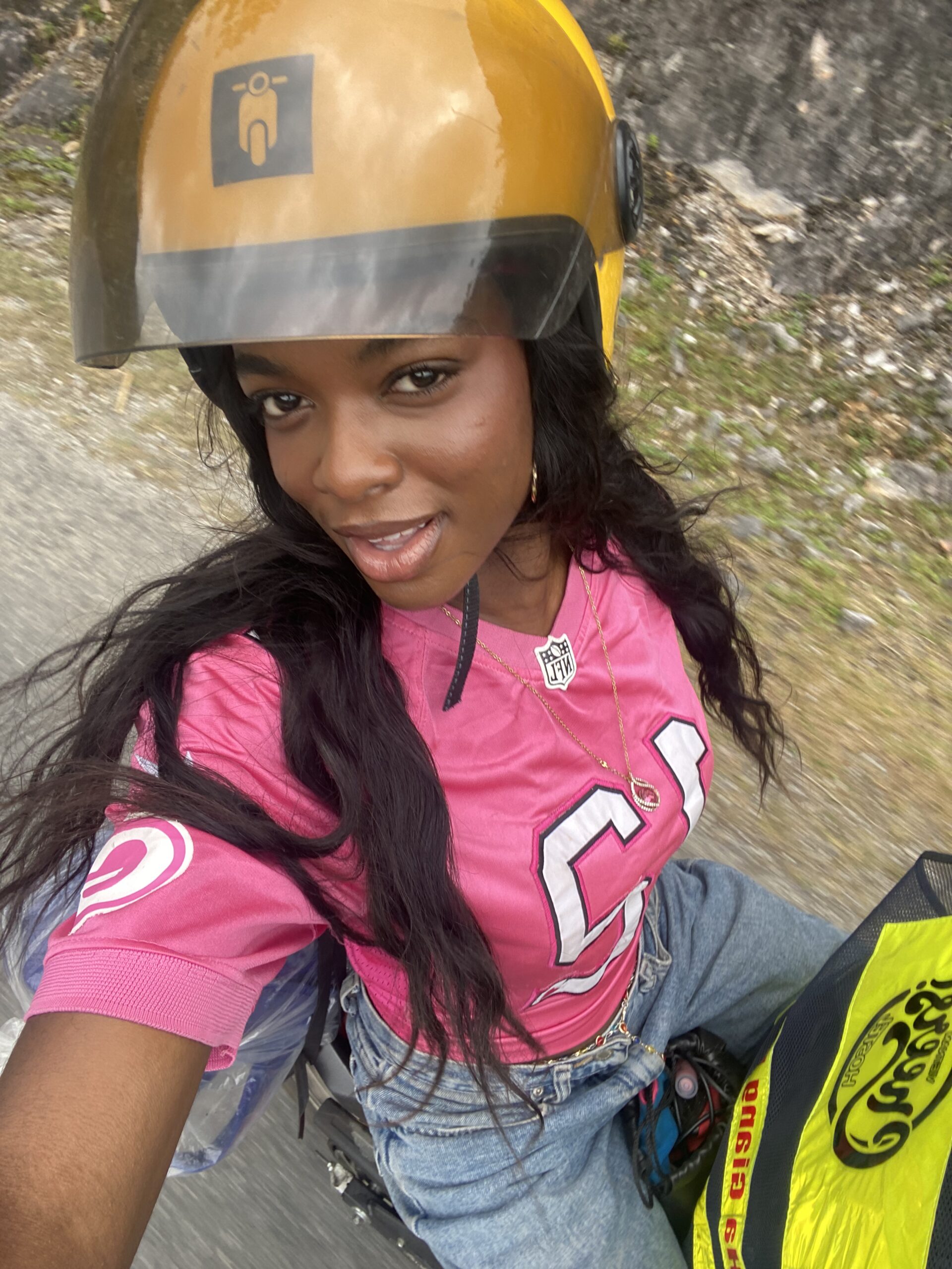 Solo traveler riding on the back of a motorbike along the Ha Giang Loop in Vietnam, wearing a pink jersey and denim jorts — introducing my travel blog about adventure, culture, and exploring Southeast Asia