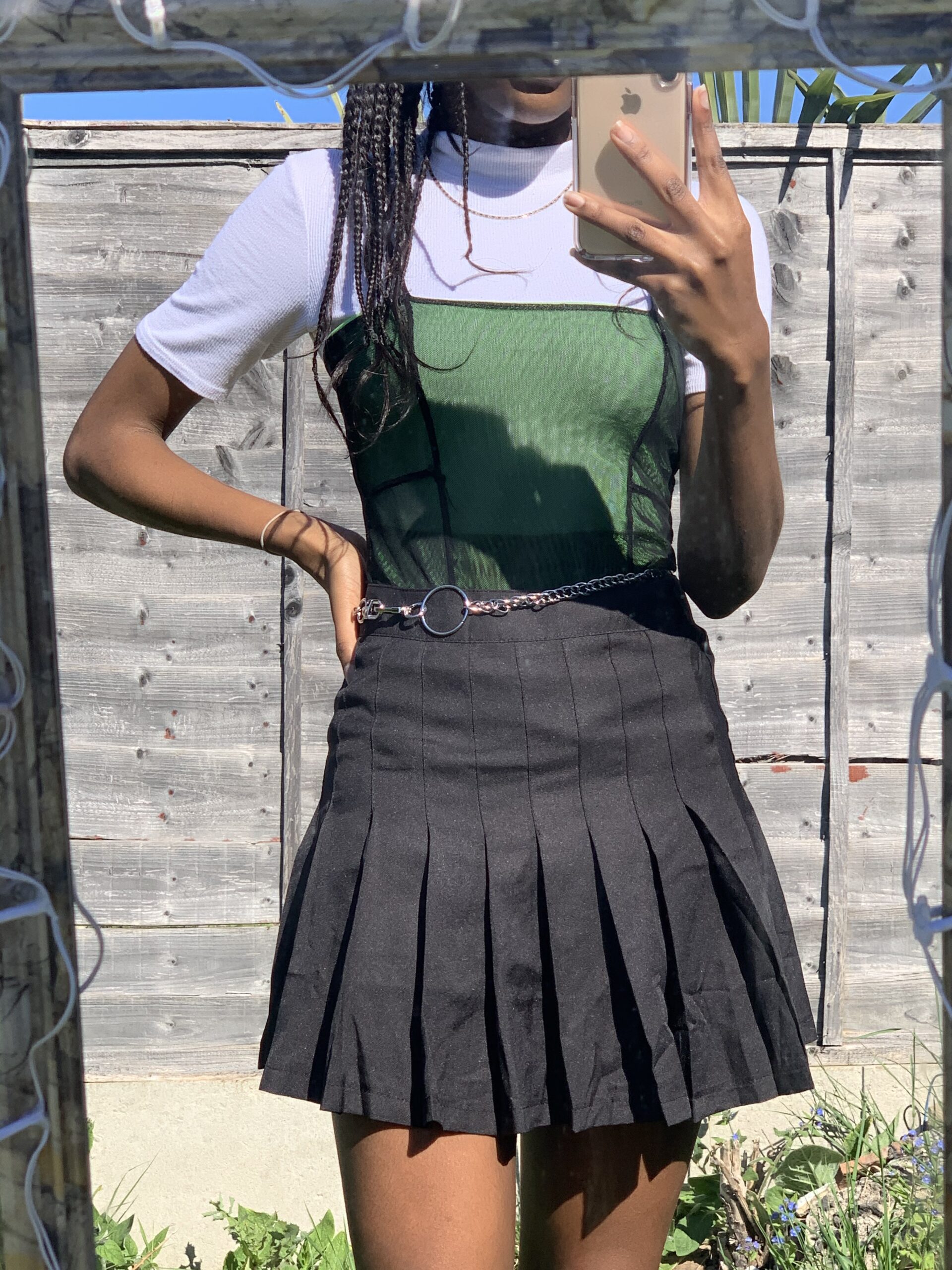 How to actually develop a personal style Photo of me in a green bodysuit layered over a white undertop with a black pleated mini skirt and chain, capturing an edgy, layered look that showcases my shift toward more alternative and expressive styling.