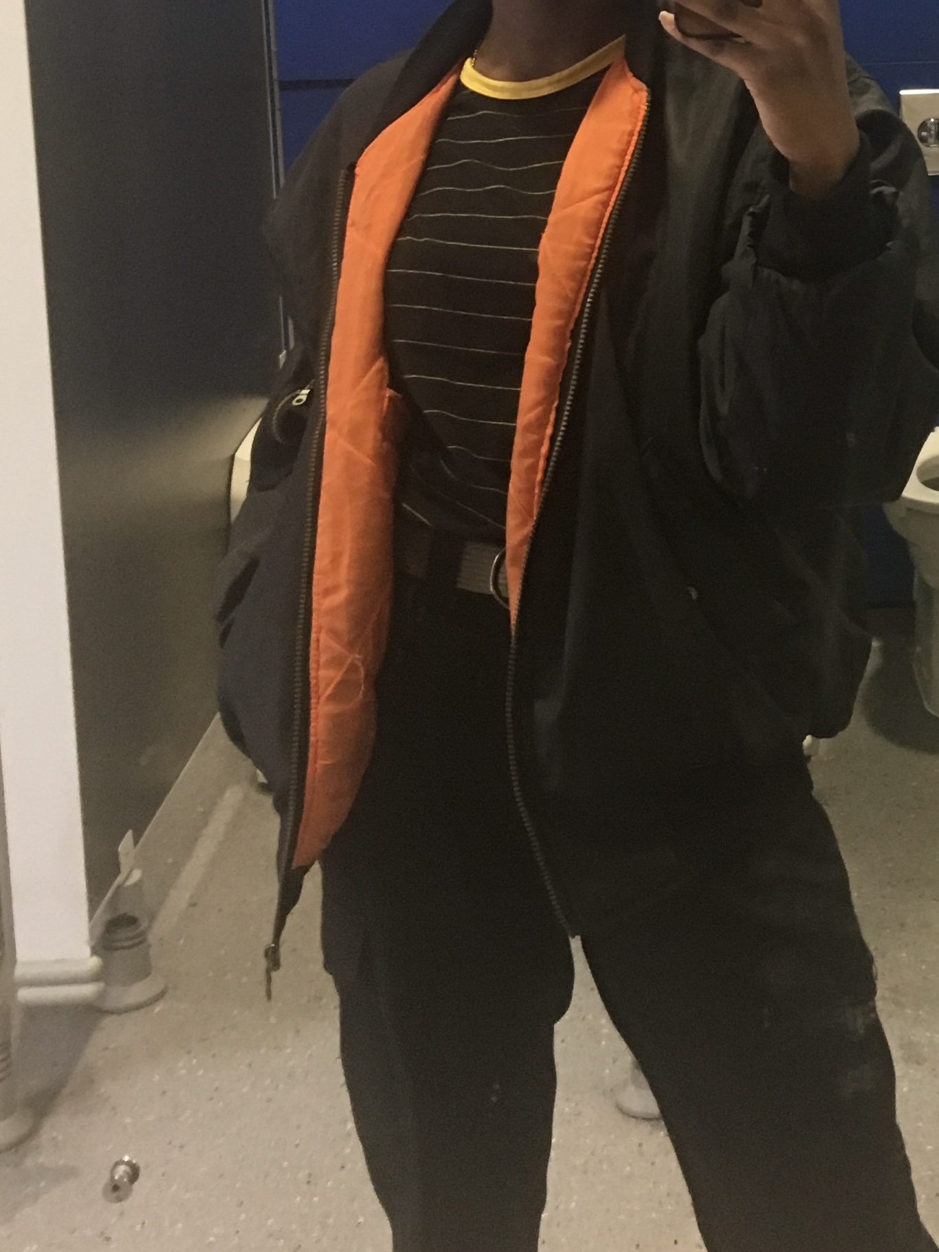 How to actually develop a personal style Mirror selfie of me in a black puffer jacket, yellow striped tee, and black cargos, highlighting a streetwear-inspired stage in my style journey focused on comfort, edge, and everyday outfit experimentation.