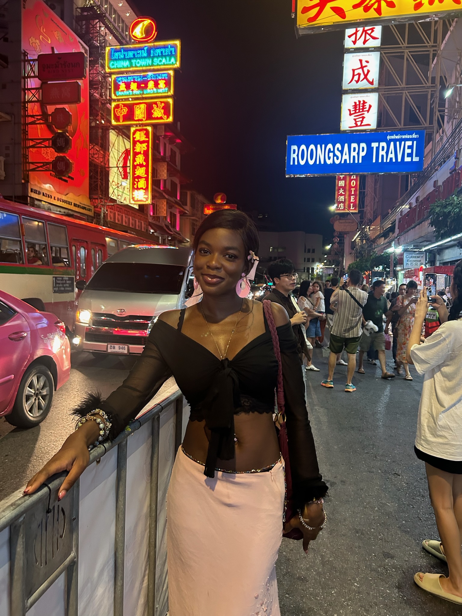 Traveler exploring Bangkok Chinatown surrounded by neon signs, street food stalls, and busy evening crowds on Yaowarat Road